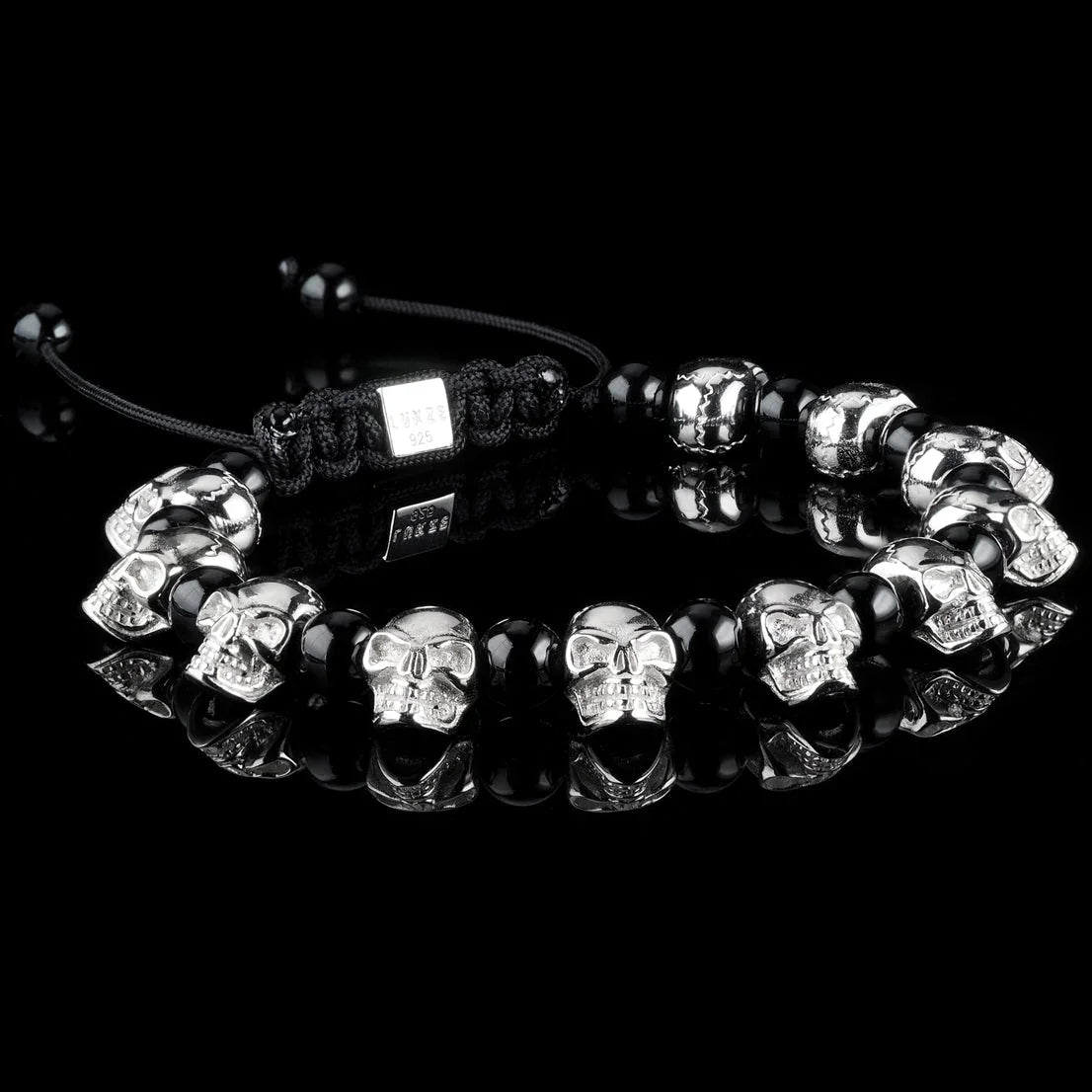 Lukze 925 sterling silver skull and black onyx macramé bracelet on a black reflective surface