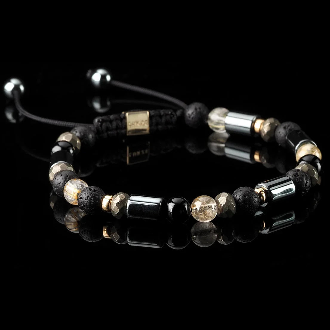 Lukze Tutankhamun Macramé Bracelet with black lava stones and gold accents on a black background