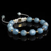Lukze Amazonite and gold macramé beaded bracelet on a black reflective background.
