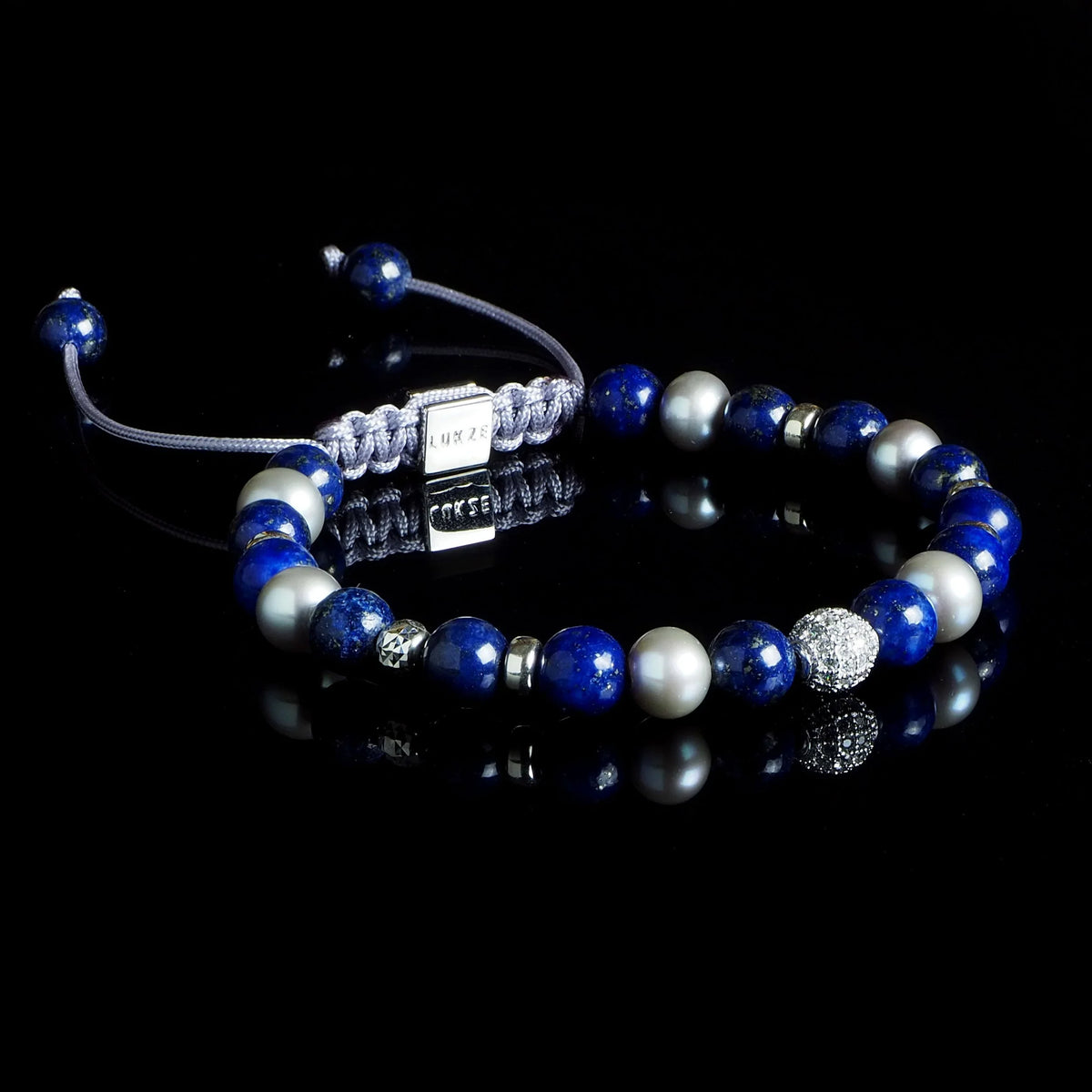 Lukze Snow White Macramé Bracelet with blue and white beads on a black reflective surface