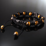Lukze yellow tiger's eye Shamballa bracelet with black cord on a reflective surface